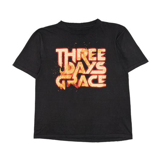 A black short-sleeve t-shirt featuring a large, stylized 'THREE DAYS OF GRACE' graphic printed on the chest in a fiery orange and yellow textured font, displayed against a solid white background.