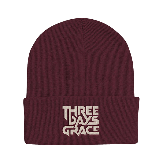 A ribbed knit cuffed beanie in deep burgundy with a light beige embroidered logo reading 'THREE DAYS GRACE' on the front cuff, shown against a plain white background.